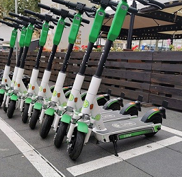 Foto: Auf dem Foto sind E-Scooter zu sehen, die in einer Reihe nebeneinander aufgestellt wurden. 