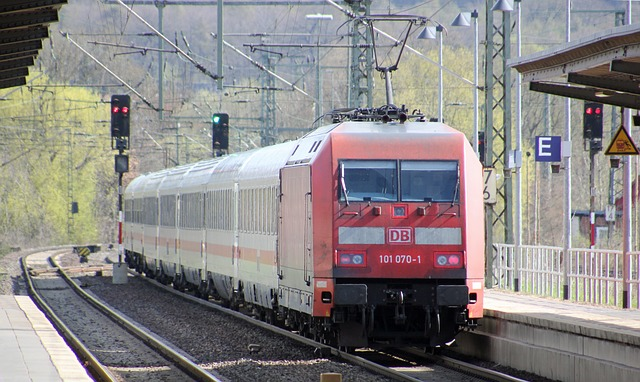 Bildbeschreibung: Auf dem Bild ist ein IC Zug zu sehen, der gerade in einen Bahnhof einfährt. Rechts und links der Gleise ist der Bahnsteig mit Überdachung angedeutet. Im Hintergrund des Bildes in der Bildmitte sind Signale zu sehen. Neben den Gleisen im Hintergrund sind Bäume zu sehen. Ende der Bildbeschreibung.