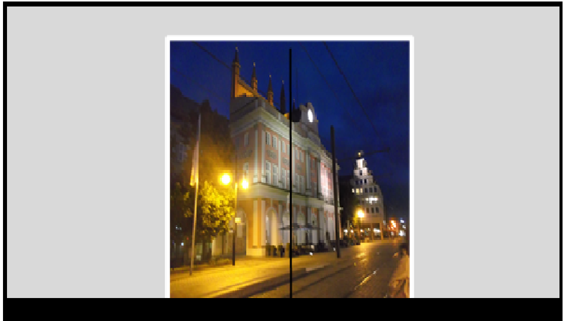 Bildbeschreibung: Blick durch eine Glastür zum nächtlich beleuchteten Rostocker Rathaus. Ende der Bildbeschreibung.