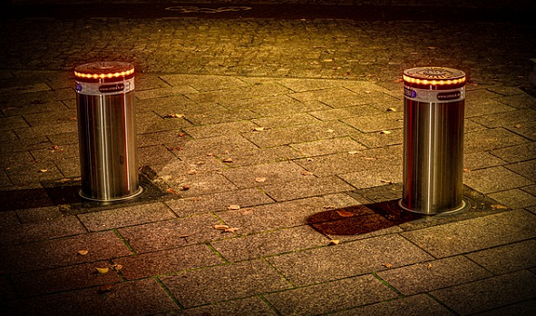 Bildbeschreibung: Das Bild 1 zeigt 2 im Abstand nebeneinander stehende beleuchtete Poller auf einem Gehweg bei Nacht. Ende der Bildbeschreibung.