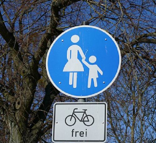 Bildbeschreibung: Bild 3 zeigt ein rundes Verkehrszeichen mit weiß auf blauen Hintergrund abgebildeten Frau (links) mit Kind (rechts). Unterhalb diesem ist zusätzlich ein weißes rechteckiges Schild mit schwarzem Rahmen angeordnet. In dessen Mitte ist ein schwarzes Fahrrad abgebildet, worunter das Wörtchen „frei“ in schwarzen Kleinbuchstaben steht. Ende der Bildbeschreibung.