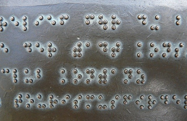 Bild 1 zeigt Brailleschrift auf einer Metallplatte.