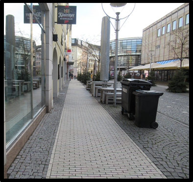 Bild 3 zeigt einen Blick entlang eines Gehweges; der Sicherheitsraum zwischen Gehbahn und Fahrbahn ist mit zahlreichen Hindernissen zugestellt.