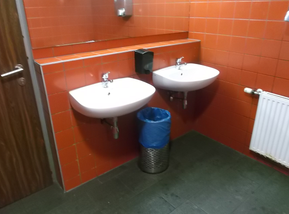 Bild 3 zeigt 2 weiße Waschbecken an einer orange gefliesten Wand im Herren-WC im Cafe des Riesenrates (rechts neben dem Eingang) auf dem Prater .
