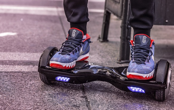 Bild 2 zeigt eine auf einem Hoverboard stehende Person auf einem Gehweg. 