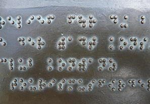 Bild 3 zeigt Brailleschrift auf einer Bronzeplatte. 