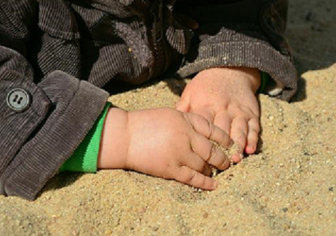 Bild 1 zeigt Kinderhände, die feinen Sand fühlen.