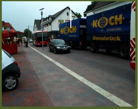 Bild 3 zeigt eine durch einen weißen Streifen abgetrennte Straße (rechts, wo Busse und LKWs fahren) vom Fußgängerbereich (links, wo sich Fußgänger befinden)