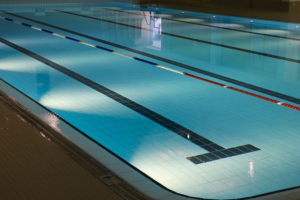 Bild 6: Kontrastreiche Schwimmbahnmarkierung durch schwarze Fließen im Beckenboden und blau-rot-weiß gestreifte Ketten auf der Wasseroberfläche.