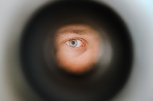 Bild 3: Mann sieht mit einem Auge durch einen runden Türspion. 