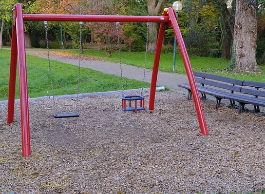 Bild 2: 2 Schaukeln mit rotem Gerüst - rechts mit Sitz für Kleinkinder, links für ältere Kinder